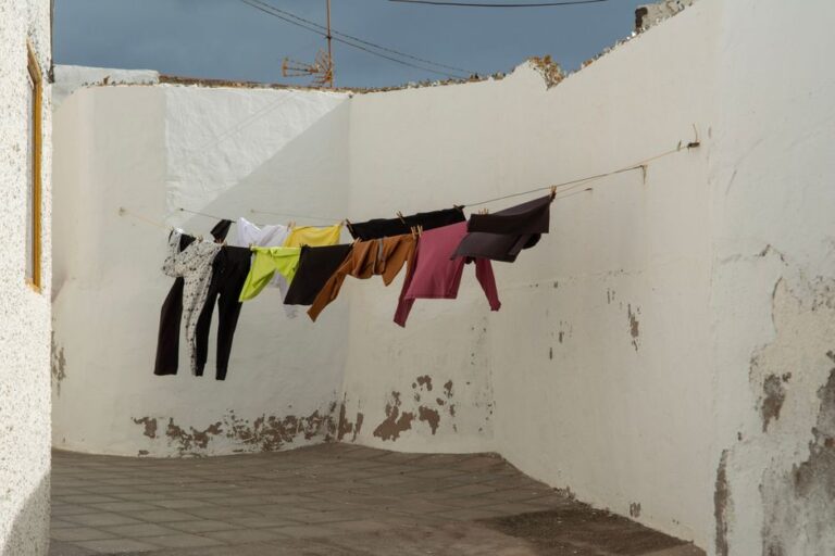 Linge de toutes les couleurs qui sèche sur une corde entre des murs blancs