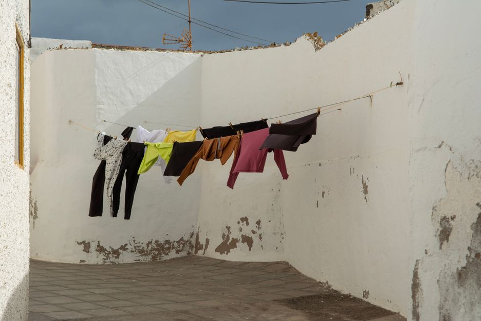 Linge de toutes les couleurs qui sèche sur une corde entre des murs blancs