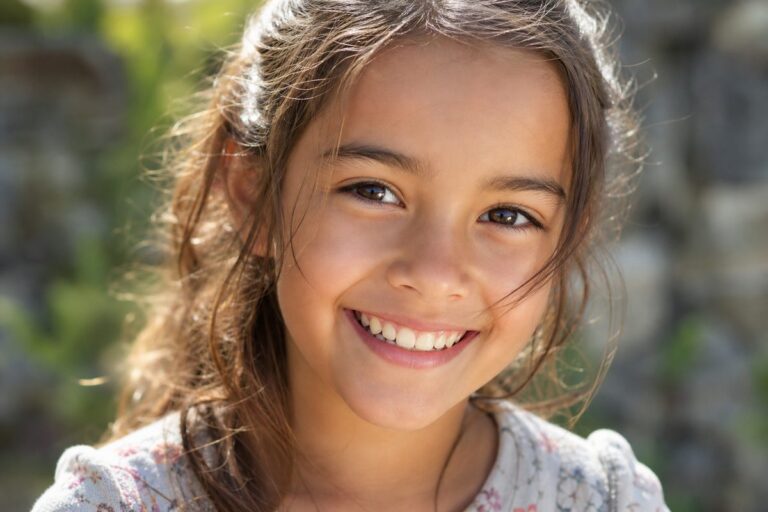 Fillette souriante en plein soleil, les yeux bien visibles