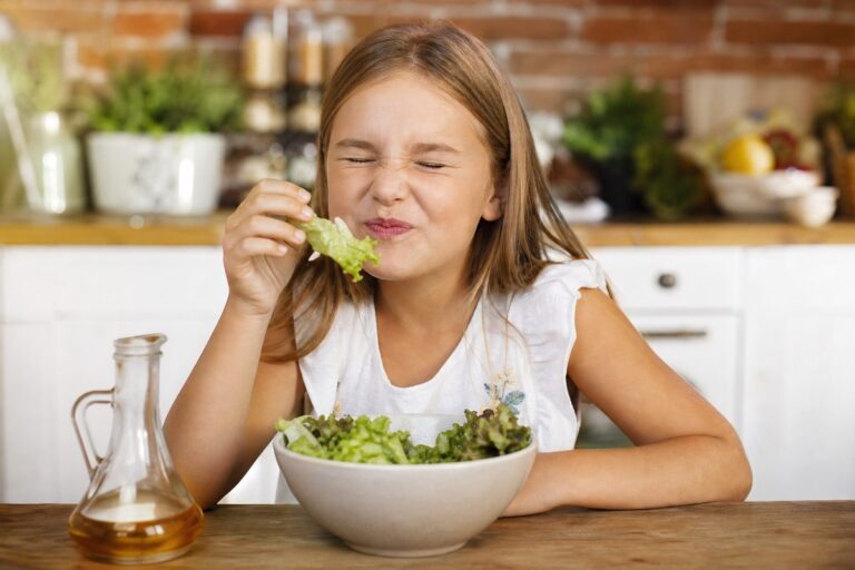 Fillette qui grimace en goûtant une salade vinaigrée